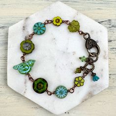 a bracelet with green and blue glass beads on a white marble slabd hexagonal object