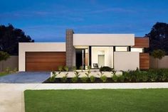 a modern house is shown at night with its lights on and landscaping in the foreground