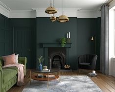 a living room with dark green walls and wood flooring is furnished with a sofa, chair, coffee table and fireplace