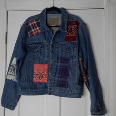 a denim jacket with patchwork and patches hanging on a door