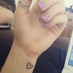 a woman's hand with a small heart tattoo on it