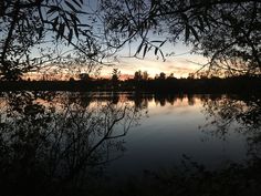 the sun is setting over a calm lake