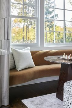 a living room with a couch, table and chess board on the coffee table in front of two windows