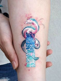 a woman's arm with a tattoo on it and a dragon in the water