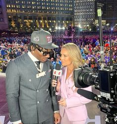 a man and woman standing next to each other in front of a camera