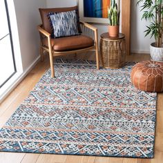 a living room area with a rug, chair and potted plant