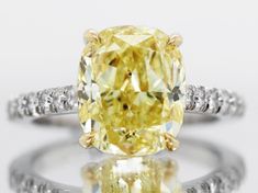 a fancy yellow diamond ring with diamonds around the band and an oval cut center stone