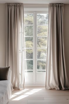 an open window with curtains in front of it and a white bed on the other side