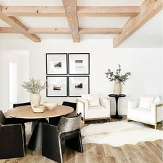 a living room filled with white furniture and wooden beams on the ceiling over a hardwood floor