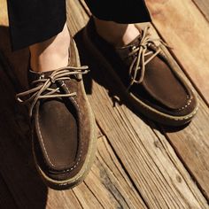 a person wearing brown shoes standing on a wooden floor