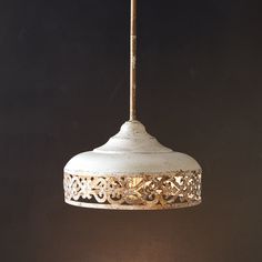 a white light hanging from a ceiling with an intricate design on the top and bottom