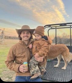 a man holding a little boy in his arms while sitting on the back of a truck