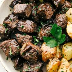 a white bowl filled with meat and potatoes