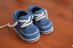 a pair of blue crocheted baby shoes sitting on top of a wooden table