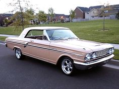 an old car is parked on the side of the road in front of some houses