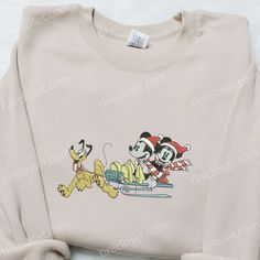 Mickey Minnie And Pluto Sleigh Embroidered Shirt, Disney Characters Embroidered Hoodie, Best Christmas Gifts For Family Welcome to Tinicloset, the enchanting emporium of custom embroidered apparel that’s here to elevate your festive fashion game. At Tinicloset, we’ve reimagined the holiday spirit through the lens of our creative embroidery, delivering an experience that goes beyond ordinary clothing. Imagine Mickey, Minnie, and Pluto having the time of their lives on a sleigh ride – Disney Embroidered Long Sleeve Sweatshirt, Disney Cotton Sweatshirt For Winter, Winter Disney Cotton Sweatshirt, Disney Crew Neck Hoodie For Winter, Christmas Gifts For Family, Embroidered Apparel, Creative Embroidery, Sleigh Ride, Family Christmas Gifts