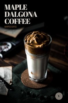 a cup of coffee sitting on top of a table next to a book and pen