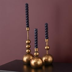 three gold and black candlesticks sitting on top of a table next to each other