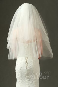 the back of a bride's wedding dress with a veil on her head is shown