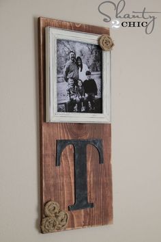 a wooden frame with an iron letter hanging on the wall next to a photo and rope