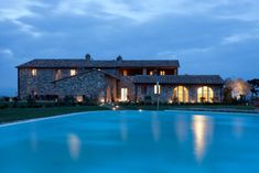 a large house with a pool in front of it at night, lit up by lights on the windows