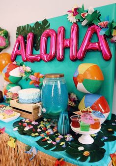 there is a table with balloons and other items on it that say aloha