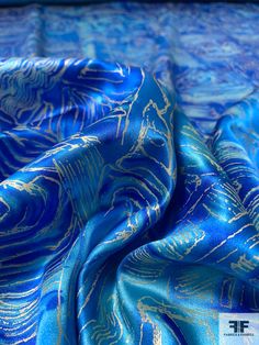 a blue and gold patterned fabric on top of a bed