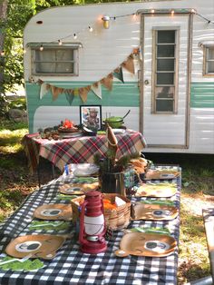 a picnic table with plates, cups and utensils on it in front of an rv