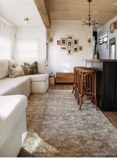 a living room filled with furniture next to a kitchen and dining room table on top of a rug