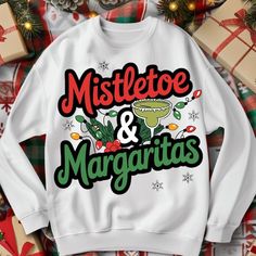 a white sweatshirt with mistleto and margaritas on it sitting next to presents