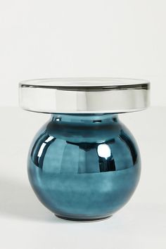 a blue vase sitting on top of a white table next to a metal container with a silver lid