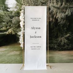 a white sign sitting on top of a table next to a lush green park filled with trees