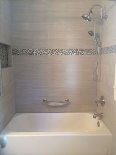 a white bath tub sitting inside of a bathroom next to a shower head and hand rail