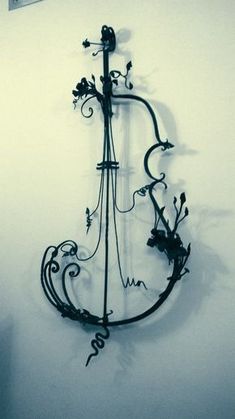 a metal sculpture with vines and flowers hanging from it's side on the wall