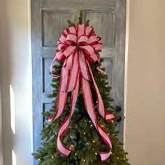 a christmas tree with a red and white bow hanging from it's front door