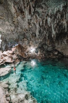 a man swimming in the blue cave with clear water and rock formations on either side