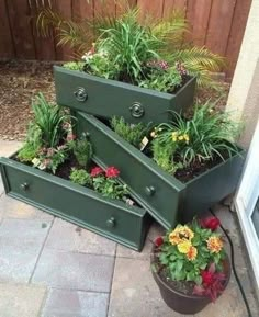 three green planters filled with different types of flowers