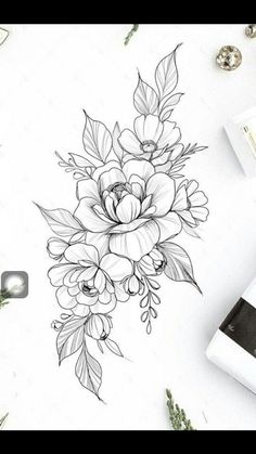 a drawing of flowers and leaves on a white paper next to some other things in the background