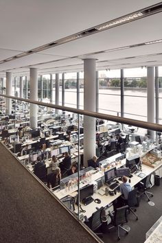 an office filled with lots of desks next to large windows and floor to ceiling windows