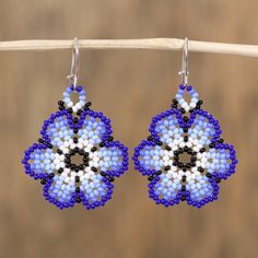 blue and white beaded earrings hanging from a wooden stick