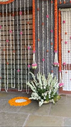 an orange and white decoration with flowers on the ground next to a wall hanging from it