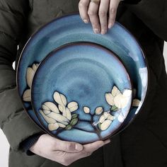 a person holding a plate with flowers painted on it