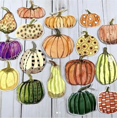 paper pumpkins and gourds are arranged on a white wooden surface with holes in the middle