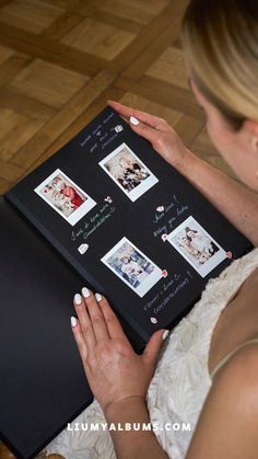 a woman in white dress holding a black book with pictures on it and writing on the cover