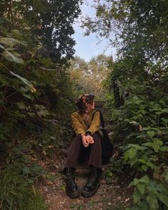 a woman sitting in the middle of a forest