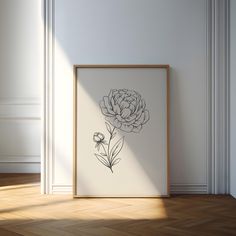 an art print with a flower on the wall next to a wooden floor in a room