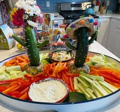 a platter filled with vegetables and dips on top of a kitchen countertop