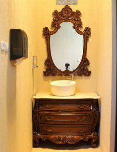 a bathroom with a sink, mirror and toilet paper dispenser