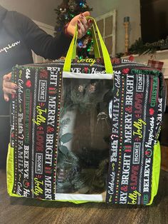 a person holding a large bag on top of a wooden table next to a christmas tree