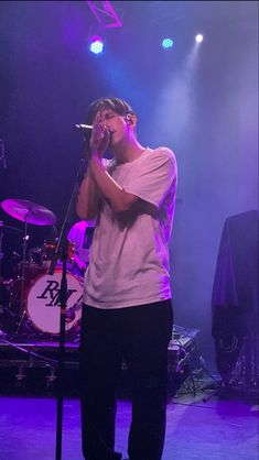 a man standing on top of a stage holding a microphone to his ear and singing